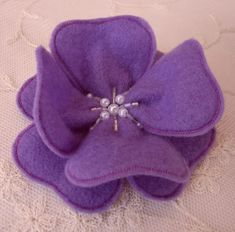 a purple flower brooch with pearls on it