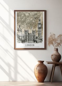 a framed london map hanging on the wall next to two vases and a table