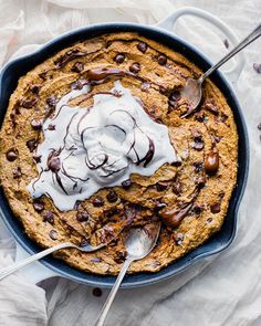 a skillet filled with chocolate chip cookie and whipped cream