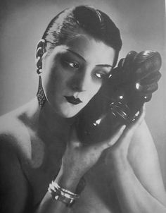 an old black and white photo of a woman holding a glove over her face with both hands