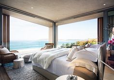 a large bed sitting in the middle of a bedroom next to a window with an ocean view