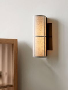 a wall light mounted on the side of a white wall next to a wooden door