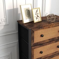 a dresser with two pictures on top of it next to a white wall and floor