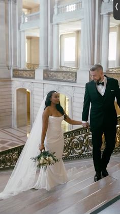 a bride and groom walking down the stairs at their wedding ceremony in an old building