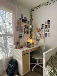 a bedroom with a bed, desk and chair next to a window filled with pictures