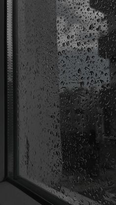 rain drops on the window pane as it is raining in front of a building