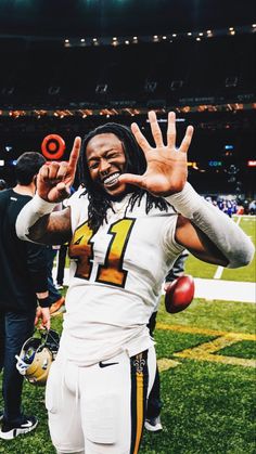 a football player is making the peace sign with his hand while standing on the field