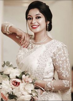 a woman in a white dress is holding a bouquet and posing for the camera with her hand on her shoulder