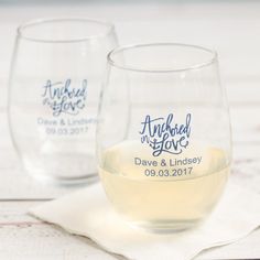 two wine glasses sitting next to each other on top of a white cloth covered table