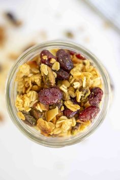 a glass jar filled with granola and raisins on top of a table