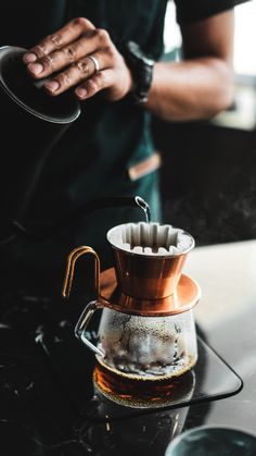 a person pours coffee into a glass pitcher