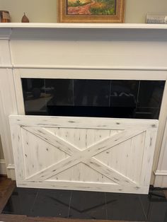 the fireplace is painted white and has a barn door on it's front side