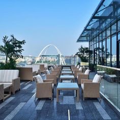 an outdoor seating area on the roof of a building with glass walls and palm trees