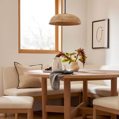 a dining room table with two chairs and a potted plant on the table next to it