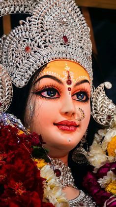 a close up of a statue with flowers in the foreground and an image of a woman's face