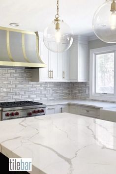 a kitchen with marble counter tops and two pendant lights hanging from the ceiling over the stove