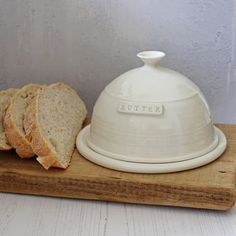 a white butter dish with slices of bread on a cutting board