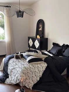 a bed with black sheets and pillows on top of it next to a mirror in a room