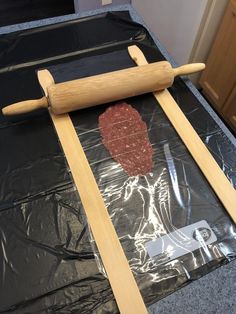 a piece of wood sitting on top of a plastic bag next to a rolling pin