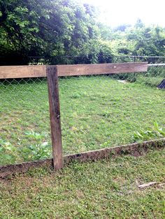 a wooden fence in the middle of a grassy field