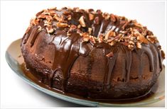 a bundt cake with chocolate icing and nuts on top