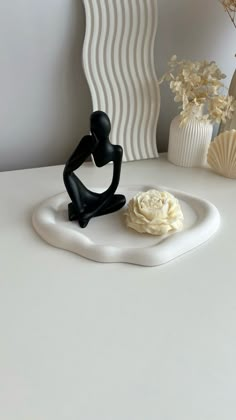 there is a small figurine sitting on a plate next to some vases