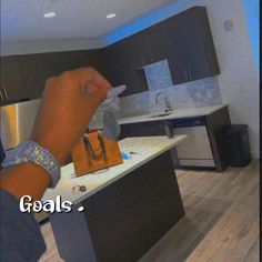 a person holding a purse in their hand with the words goals written on it and an image of a kitchen behind them