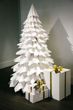 a paper christmas tree with presents under it on the floor next to a white box