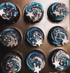 cupcakes with blue frosting and stars on them in a muffin tin