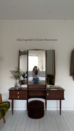 a woman is taking a selfie in the mirror while sitting at a desk with a stool