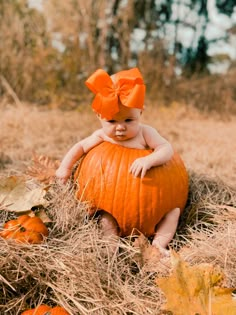 a baby sitting on top of a pumpkin