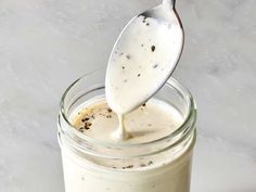 a glass jar filled with white liquid and a spoon