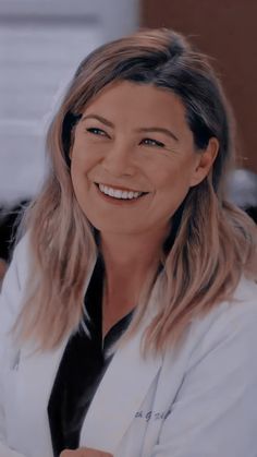 a woman with long hair wearing a white shirt and black tie smiling at the camera