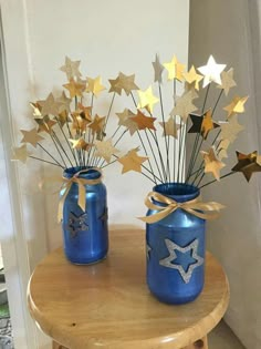 two blue mason jars with gold stars in them sitting on a table next to each other