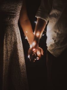 two people holding hands in the dark with lights shining on their fingers and arms together