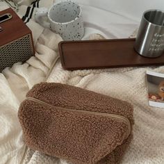 a brown purse sitting on top of a bed next to a coffee cup and radio