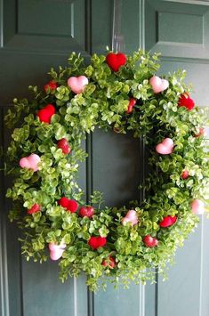 a wreath with hearts and greenery hanging on the front door for valentine's day