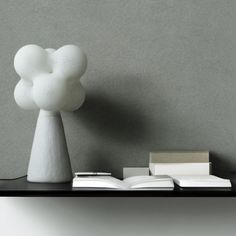 a white lamp sitting on top of a table next to a book and an open book