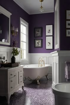 a bath tub sitting next to a white sink in a bathroom under two framed pictures