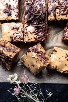 chocolate brownies with peanut butter frosting and sprinkles on a piece of parchment paper