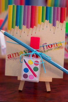 a small easel with colored pencils and a cup on it