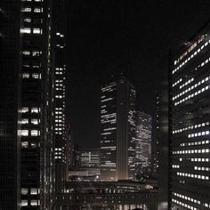 the city skyline is lit up at night, with skyscrapers in the foreground