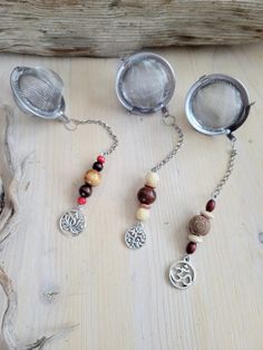 three silver tea strainers sitting on top of a wooden table