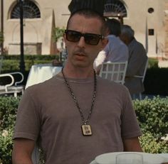 a man wearing sunglasses and a necklace with a dog tag on it