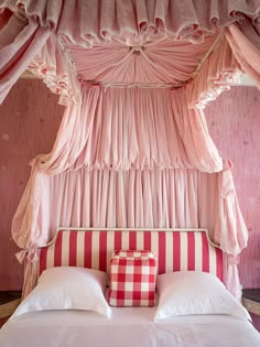 a bed with pink curtains and pillows in a room