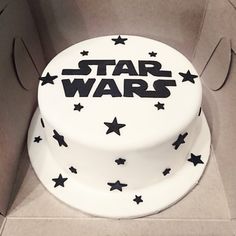 a star wars cake with black stars on the top and white frosting, sitting in a cardboard box