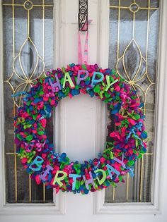 a happy birthday wreath is hanging on the front door with confetti around it