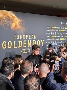 a group of people standing around each other in front of a wall with the european golden boy logo on it