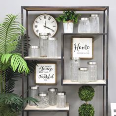 a shelf filled with vases and plants next to a clock on top of a wall