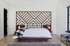 a bedroom with a large bed and wooden headboard on the wall next to a window